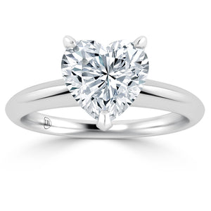 A heart-shaped diamond solitaire ring with a silver band and three prongs securing the diamond, shown on a white background. The band has a smooth, polished finish.