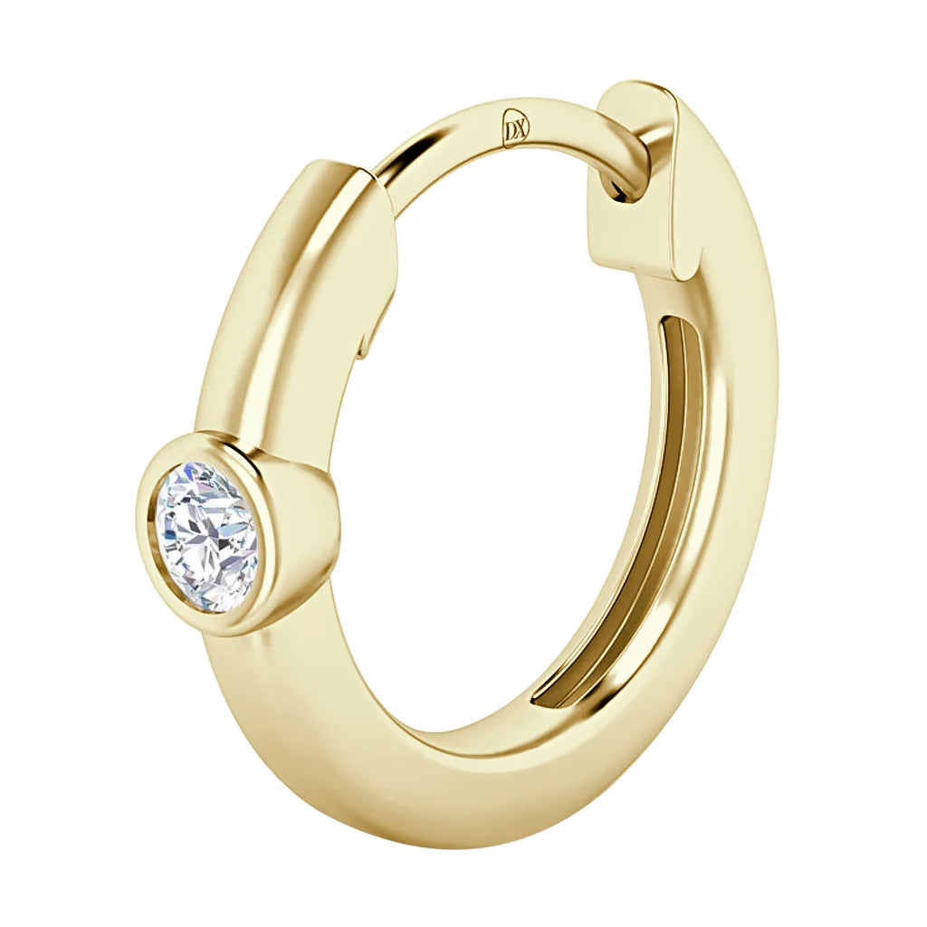 A gold hoop earring with a single round, clear gemstone set in a bezel at the front.