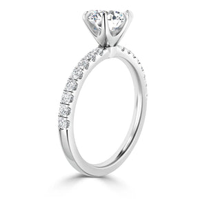 A silver engagement ring with a round solitaire diamond and smaller diamonds set along the band.