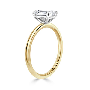 A gold ring with a thin band and a large, rectangular clear gemstone in a raised silver prong setting.