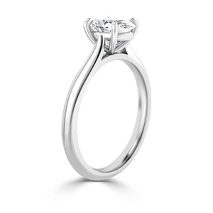 A white gold solitaire ring with a round-cut diamond set in a classic prong setting, viewed from the side.